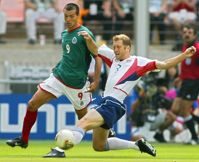 JEONJU, REPUBLIC OF KOREA:  USA's Gregg Berhalter (R) beats Mexico's Jared Borgetti (L) to the ball, 17 June 2002 at the Jeonju World Cup Stadium in Jeonju, during second round playoff action between Mexico and USA in the 2002 FIFA World Cup Korea/Japan. AFP PHOTO/ROBYN BECK (Photo credit should read ROBYN BECK/AFP via Getty Images)
